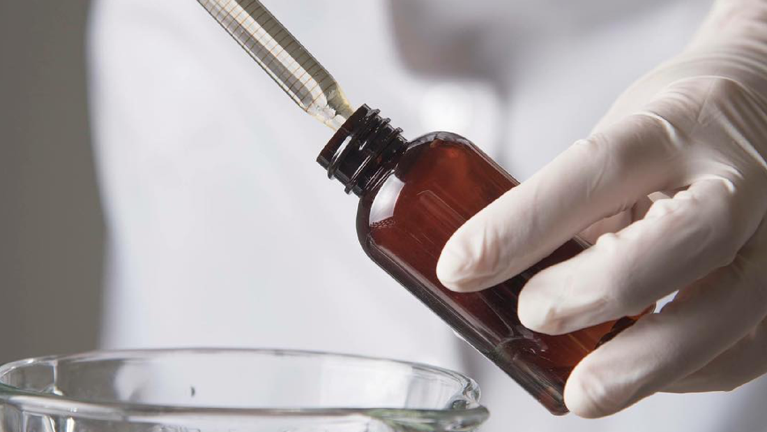 mano rellenando un frasco de vidrio con una pipeta